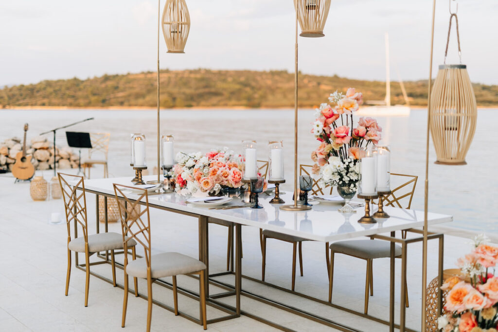 Candlelit dining table set on a dock extending into the Adriatic, bathed in golden sunset light with gentle waves lapping at the edges and a romantic ambiance.