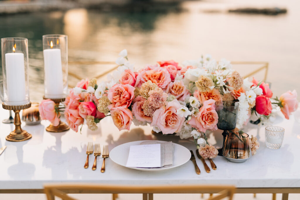 Candlelit dining table set on a dock extending into the Adriatic, bathed in golden sunset light with gentle waves lapping at the edges and a romantic ambiance.
