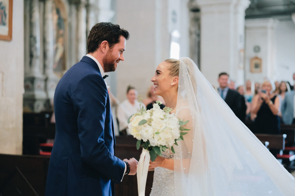 The bride and groom exchanging vows inside the historic St. Stephan Cathedral in Hvar, surrounded by soft candlelight and elegant floral arrangements.