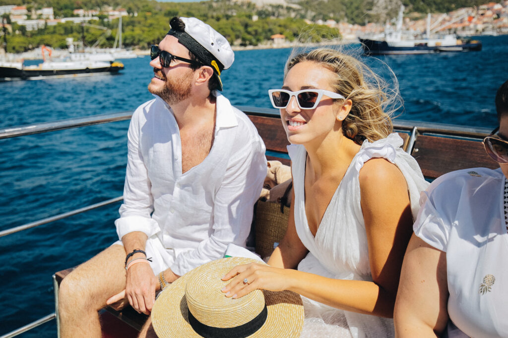Bride and groom smiling on a private boat cruising the clear blue waters around Pakleni Island during a pre-wedding excursion.