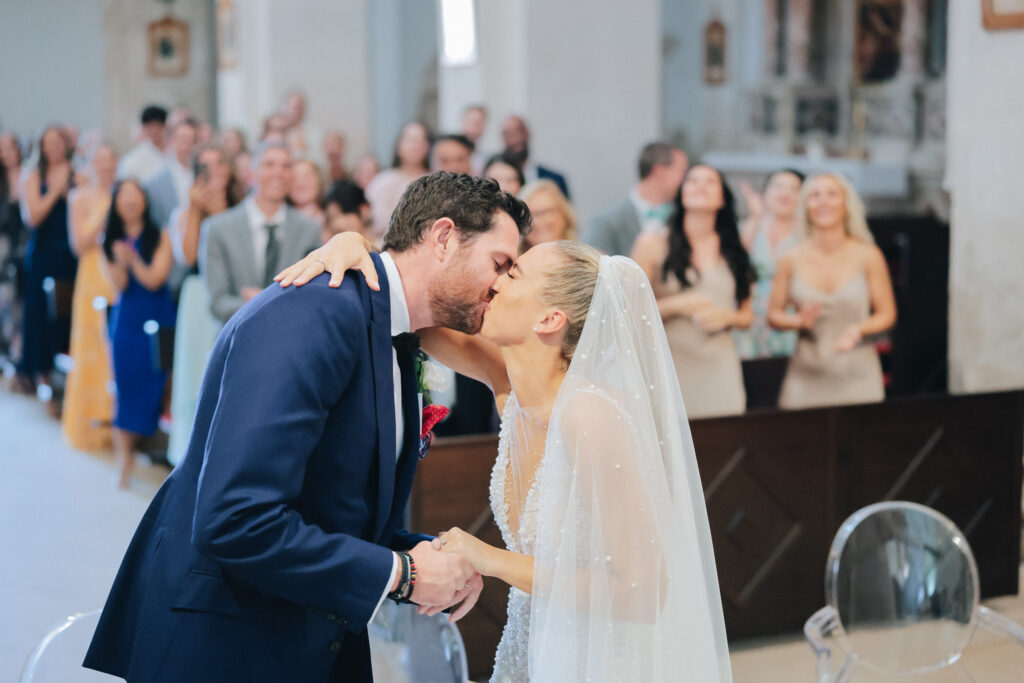 The bride and groom exchanging vows inside the historic St. Stephan Cathedral in Hvar, surrounded by soft candlelight and elegant floral arrangements.