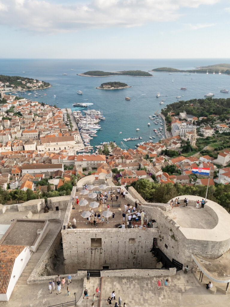 Aerial view of a historic fortress in Hvar set up for a wedding welcome party at sunset.