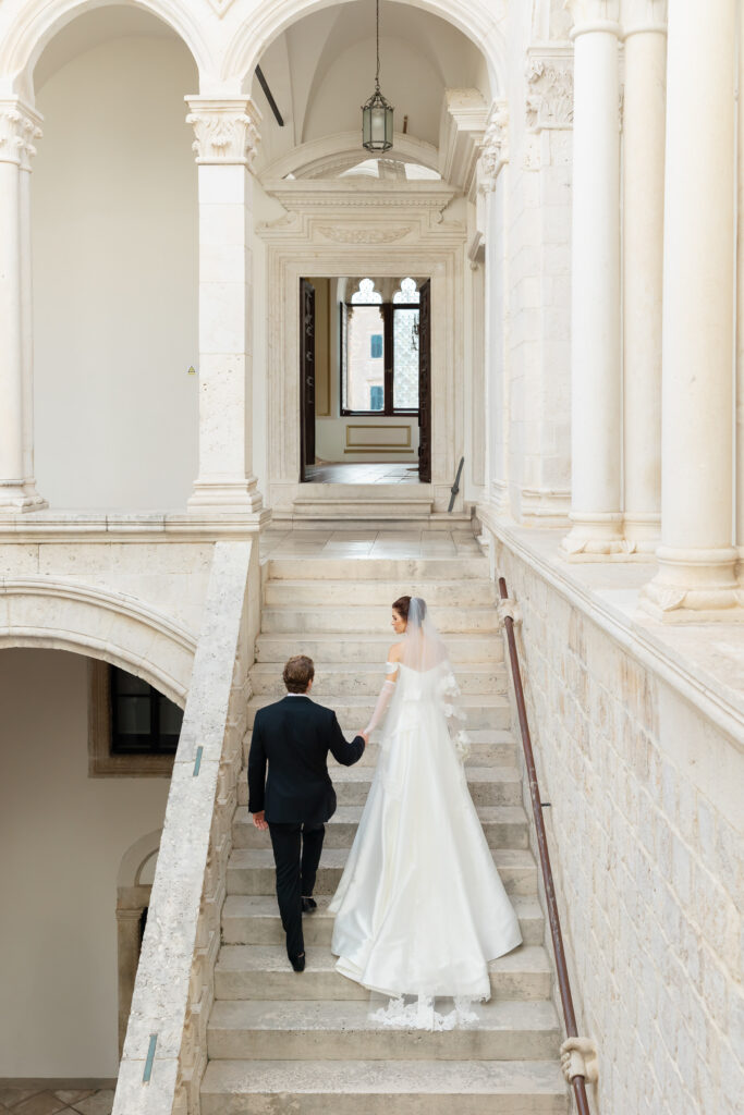 Morgan and Robbie’s three-day Dubrovnik wedding with a Hilton welcome dinner, Banje Beach party, and St. Lawrence Fortress ceremony, featuring signature cocktails, vintage bells, drummers, and a lively French band.