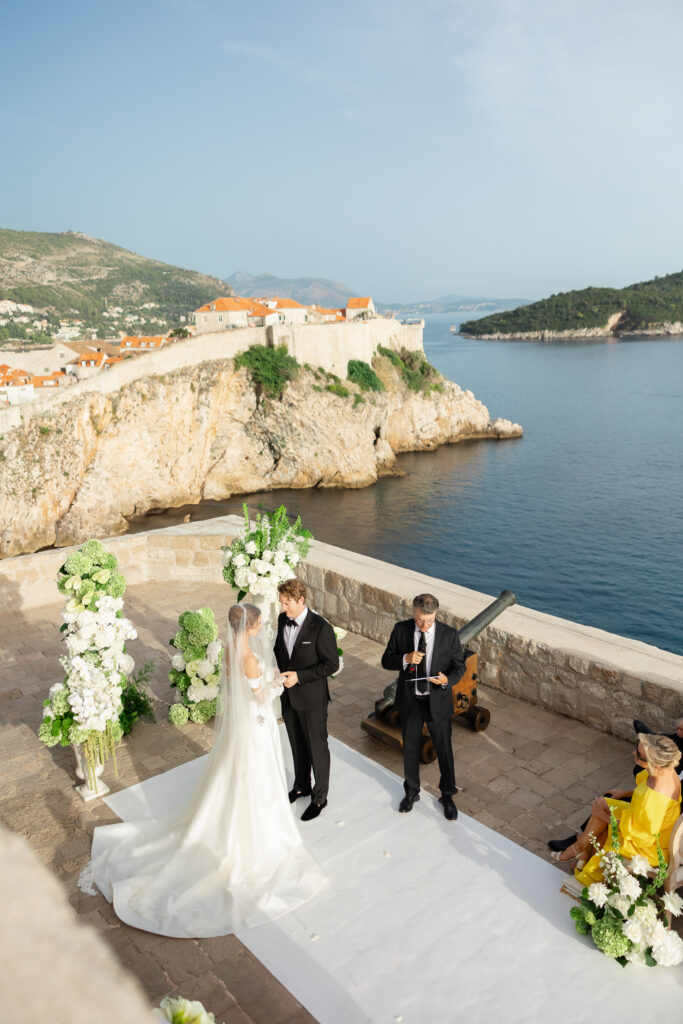 Morgan and Robbie’s three-day Dubrovnik wedding with a Hilton welcome dinner, Banje Beach party, and St. Lawrence Fortress ceremony, featuring signature cocktails, vintage bells, drummers, and a lively French band.